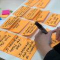 shallow focus photo of person writing on orange paper sheet