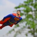 Superman flying near green grass