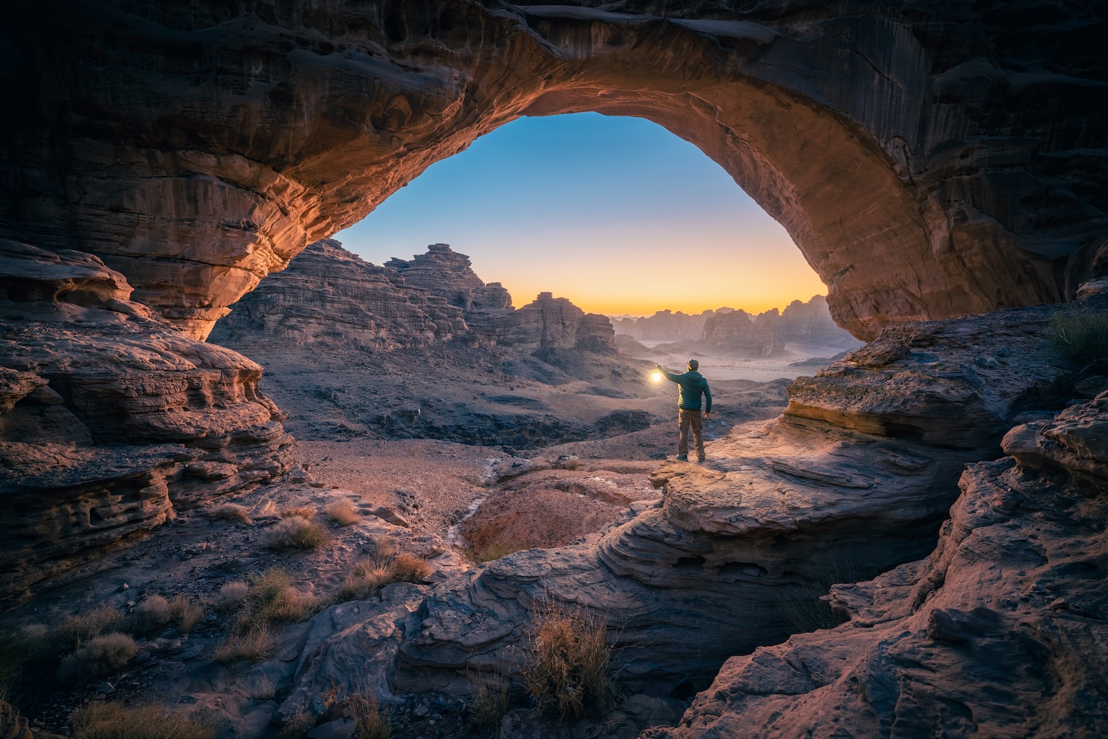 a man standing in a cave at sunset