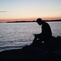 man sitting on rock in front of ocean