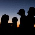 silhouette of 2 women and man standing during sunset