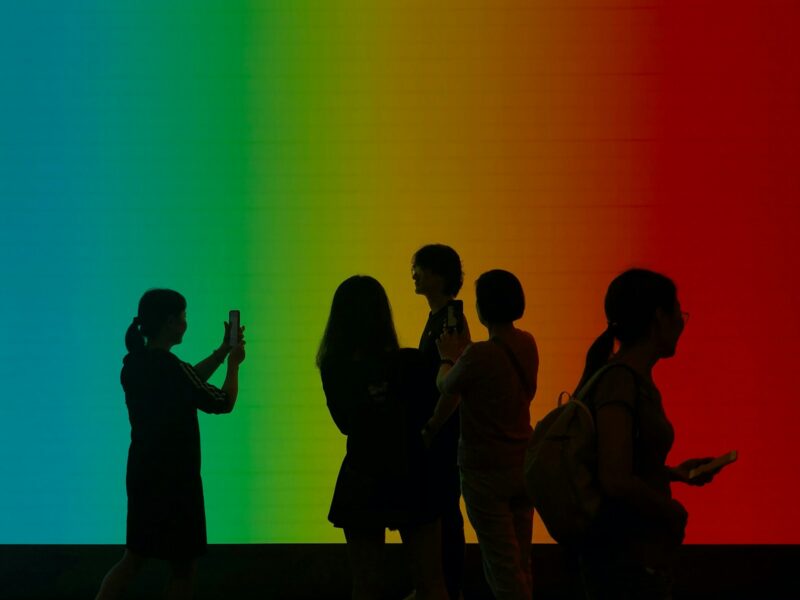 a group of people standing in front of a rainbow colored wall