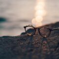 close-up photography of black framed clear lens sunglasses near body of water