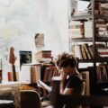 woman reading book sitting beside electronic keyboard