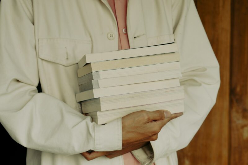 a man holding a stack of books in his hands