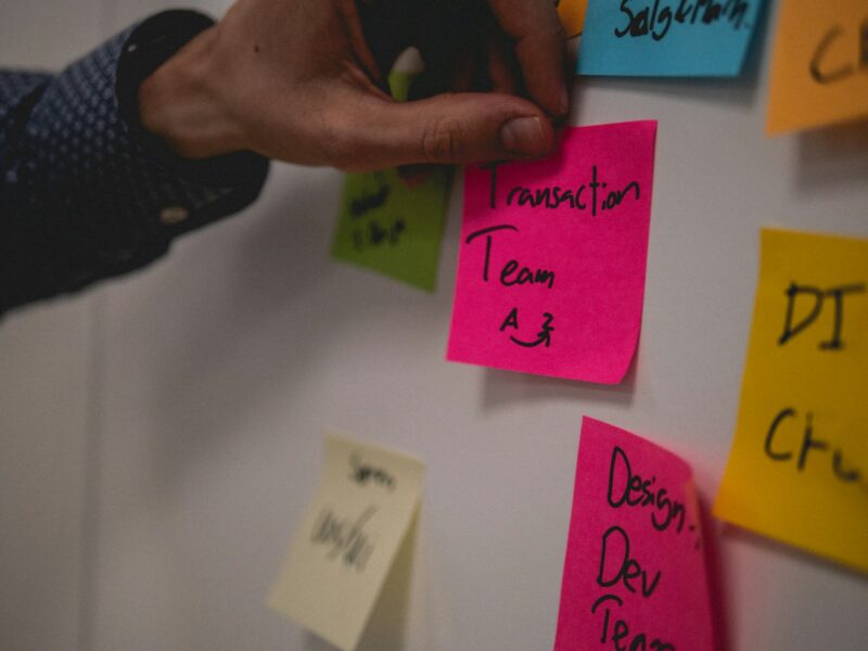 person holding pink sticky note