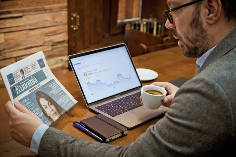 a man sitting at a table with a laptop and a cup of coffee