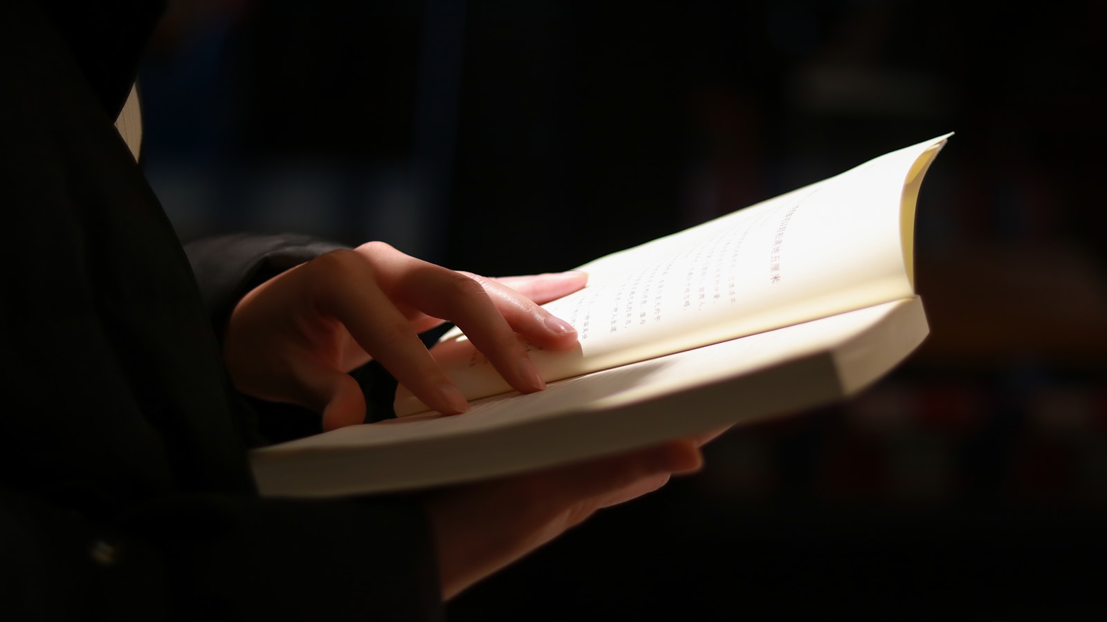 person reading book on black table